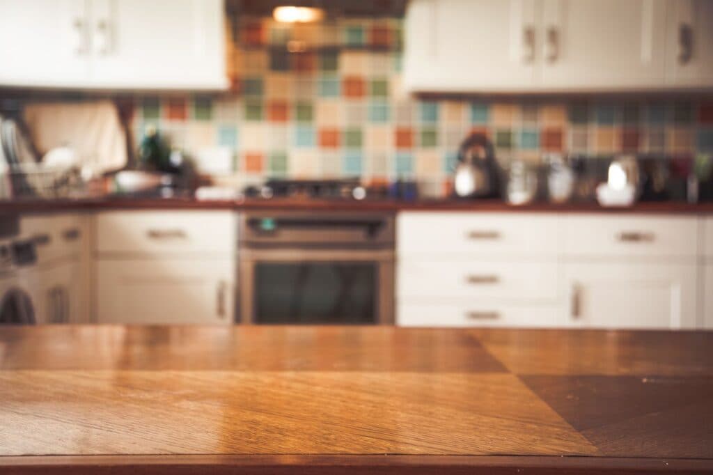 Wooden kitchen counter with blurred modern kitchen background and white cabinets