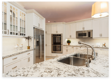 A modern kitchen featuring white cabinets, granite countertops, and elegant marble accents throughout the design.
