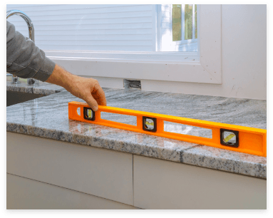 A person carefully uses a level to ensure the precision of high-quality granite countertops during installation.