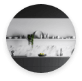 A monochromatic kitchen with white marble and slate countertops.