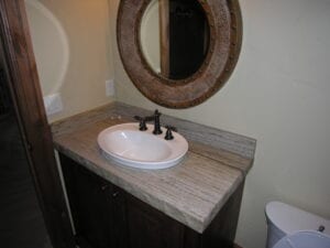 A bathroom sink with a mirror above it, reflecting the faucet and toiletries on the counter.