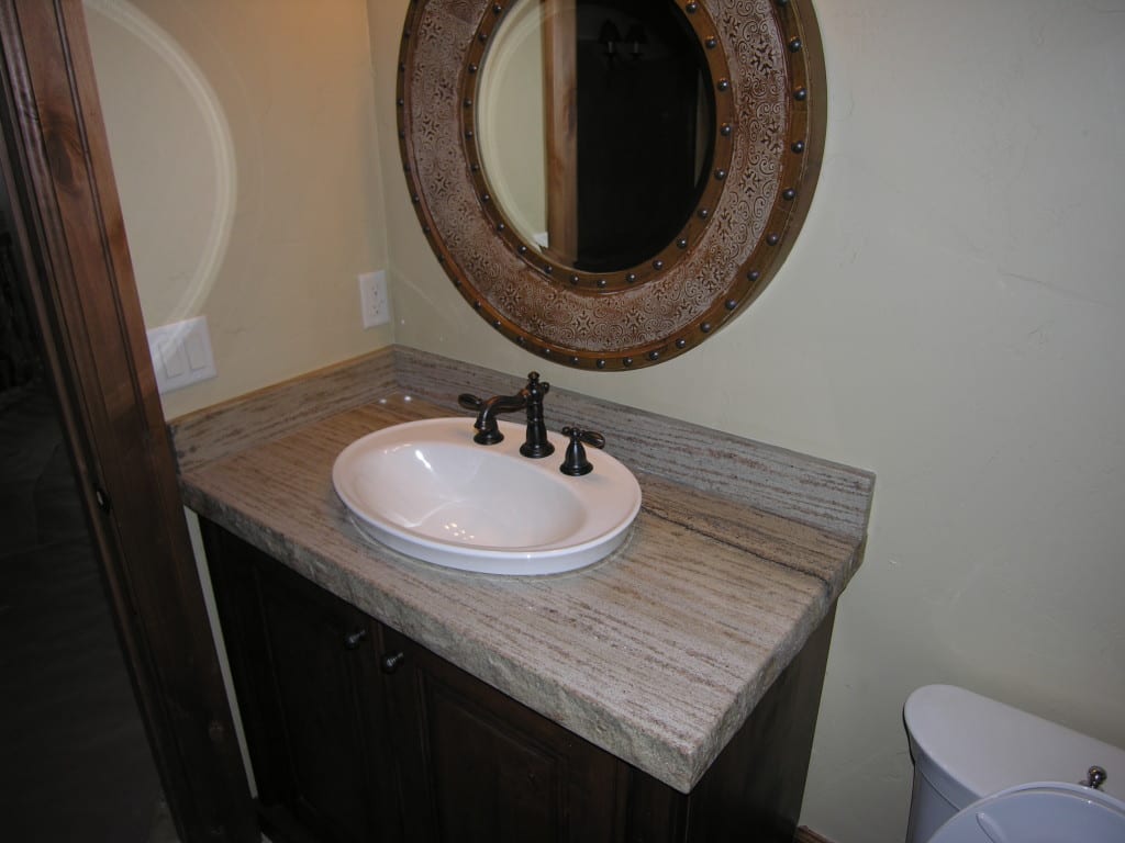 A bathroom sink with a mirror above it, reflecting the faucet and toiletries on the counter.