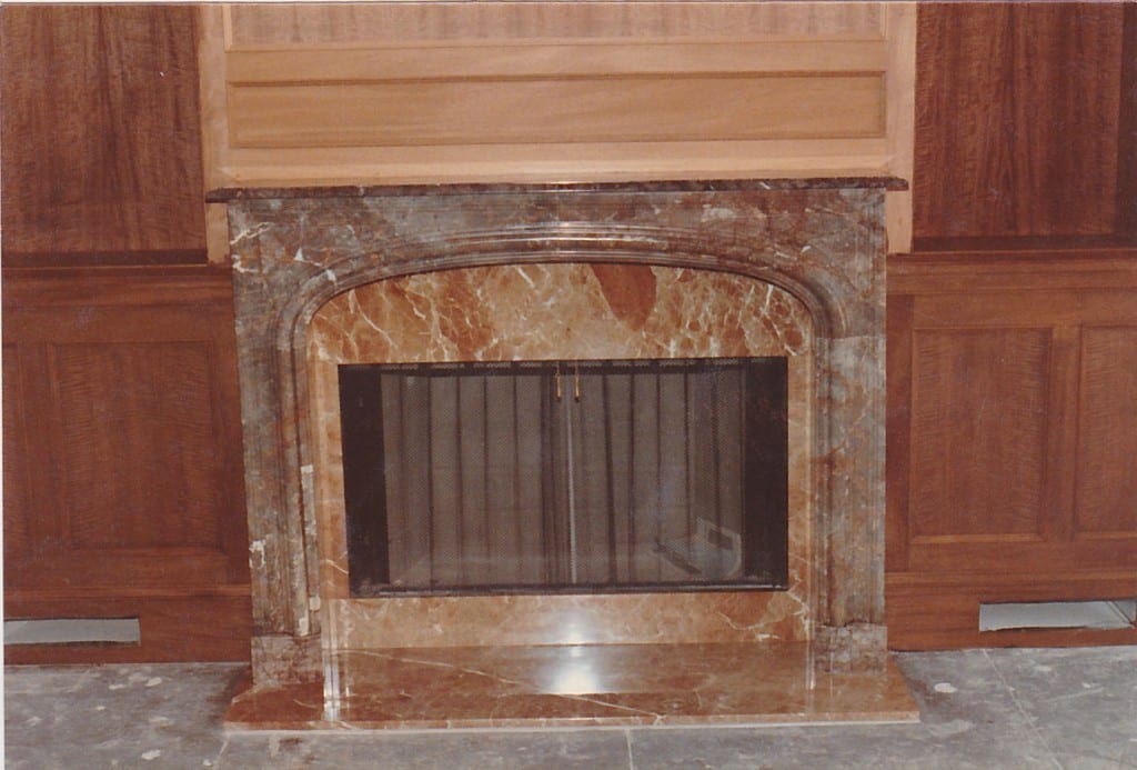 An elegant fireplace featuring a marble mantle and wood paneling, adding a touch of sophistication to the room.