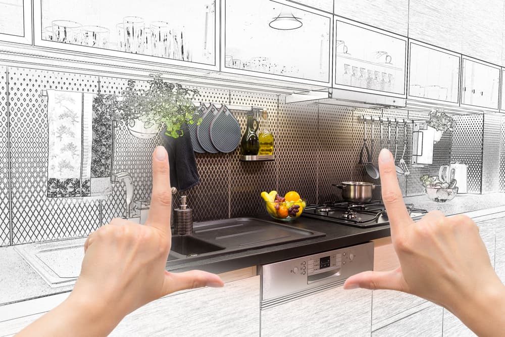 Hands frame a modern kitchen transitioning from sketch to reality, highlighting a sleek counter with a sink, fruit bowl, and stove. Tone: creative and transformative.