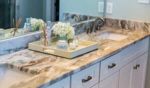 Marble bathroom vanity with dual sinks, a tray holding a candle, diffuser, and white flowers, all creating a serene and elegant ambiance.