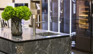 A modern kitchen with a sleek marble counter top and a stainless steel sink.