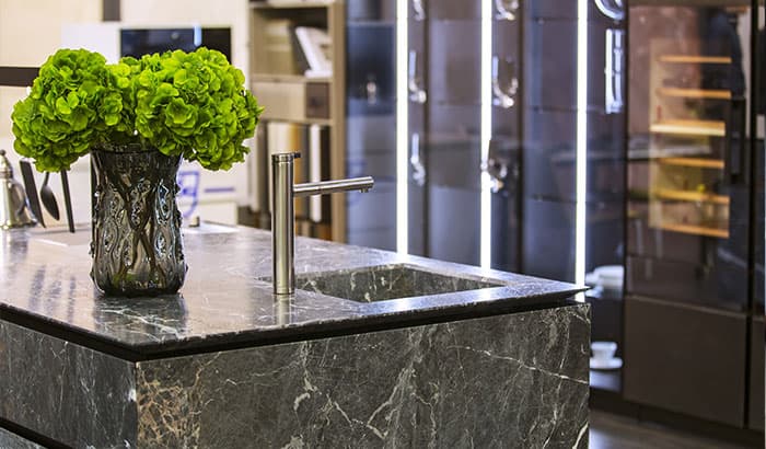 A modern kitchen with a sleek marble counter top and a stainless steel sink.