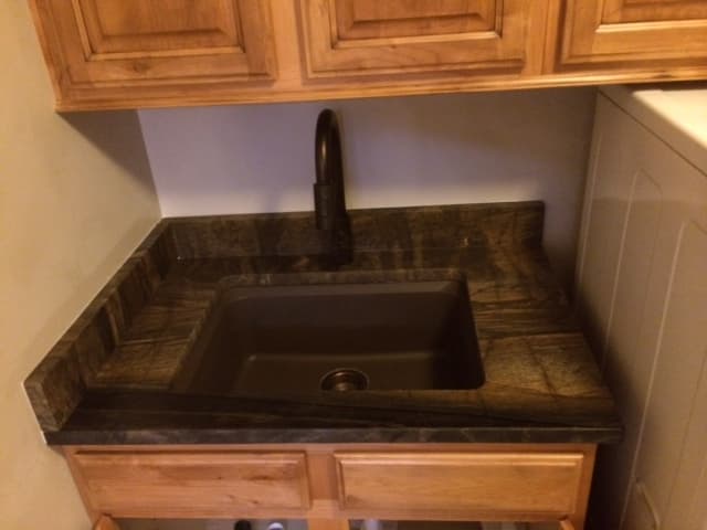 A small kitchen sink surrounded by wooden cabinets.