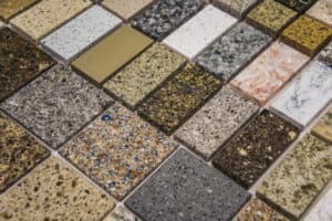 A variety of stone countertop samples are arranged in a grid. The samples display diverse textures and colors, including speckled, marbled, and solid tones.