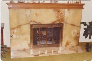 An inviting fireplace showcasing a refined marble mantle, accompanied by a flourishing plant for added warmth.