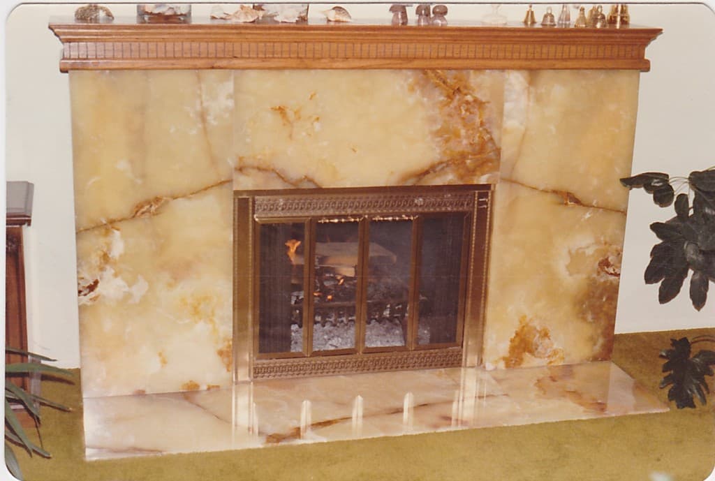 An inviting fireplace showcasing a refined marble mantle, accompanied by a flourishing plant for added warmth.