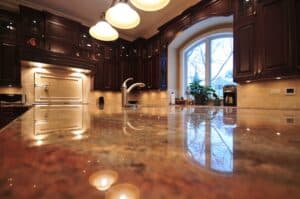 Luxurious kitchen with dark wood cabinets, granite countertop reflecting pendant lights, and a large arched window with a serene outdoor view.