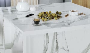 A marble kitchen countertop featuring a coffee table and a bowl of fresh fruit, creating an inviting atmosphere.