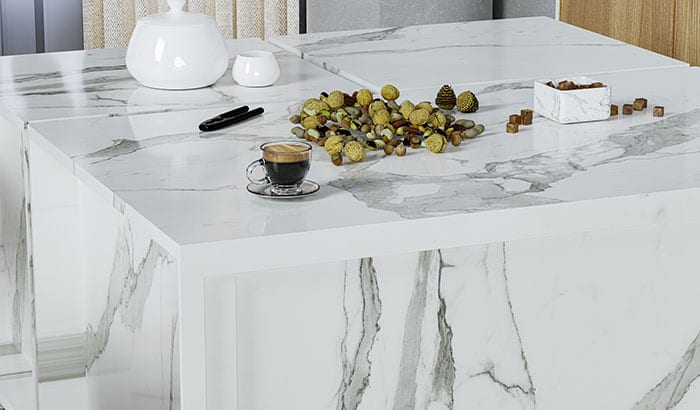 A marble kitchen countertop featuring a coffee table and a bowl of fresh fruit, creating an inviting atmosphere.
