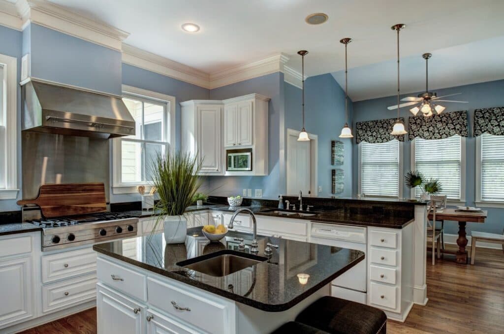 Modern kitchen with blue walls, white cabinets, black granite countertops, and a central island with a sink.