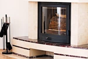 Modern indoor fireplace with glass front and stacked firewood