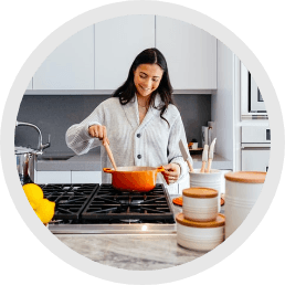 A woman cooking in the kitchen with orange pan on the stove