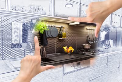 Hands frame a transition from a black-and-white kitchen sketch to a realistic, modern kitchen. The scene includes a sink, stovetop, and hanging utensils.