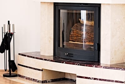 Modern indoor fireplace with glass front and stacked firewood