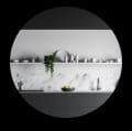 A monochromatic kitchen with white marble and slate countertops.