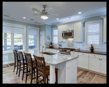 A kitchen with white cabinets and a center island, featuring quartz countertops for long-lasting color.